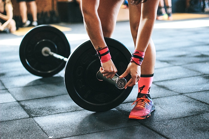 What Can I Take on a Plane in Checked Luggage - woman putting clips on barbell