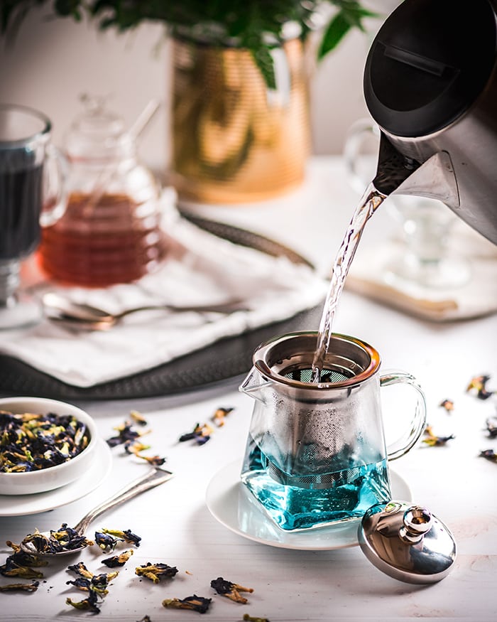 Butterfly Pea Flower Tea Latte - pouring hot water over tea leaves in teapot