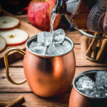 Apple Cider Mules - pouring ginger beer into copper mug