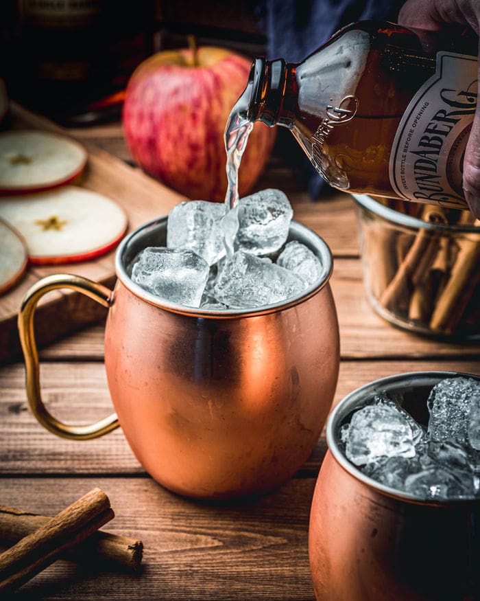 Apple Cider Mules - pouring ginger beer into copper mug