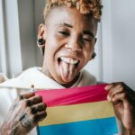 Difference between bisexual and pansexual - person holding pansexual flag