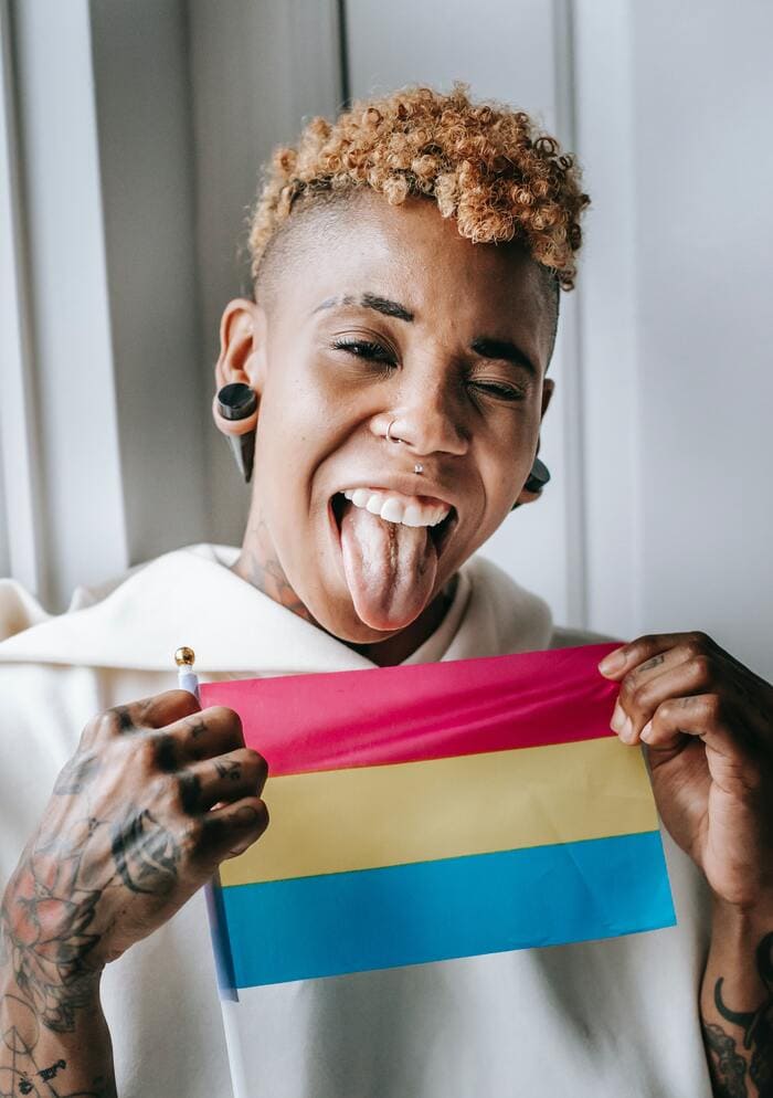 Difference between bisexual and pansexual - person holding pansexual flag