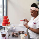 King Arthur Baking Pitchfest - black woman frosting red velvet cakes at a bakery