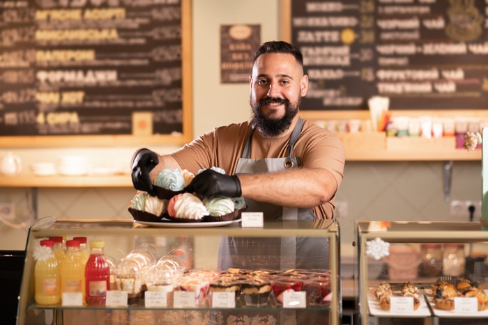 King Arthur Baking Pitchfest - coffee shop owner near showcase with cakes and desserts